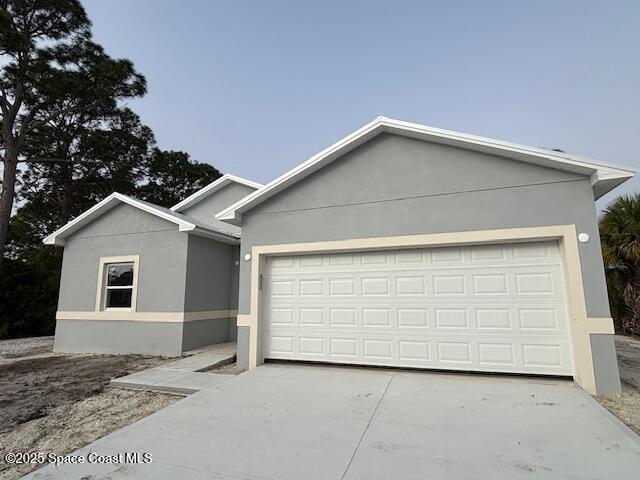 ranch-style home with stucco siding, a garage, and concrete driveway