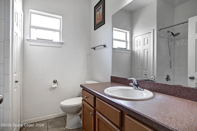 bathroom featuring a tile shower, vanity, tile patterned flooring, and toilet