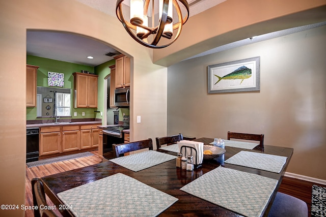 dining space featuring a notable chandelier, wood-type flooring, and sink