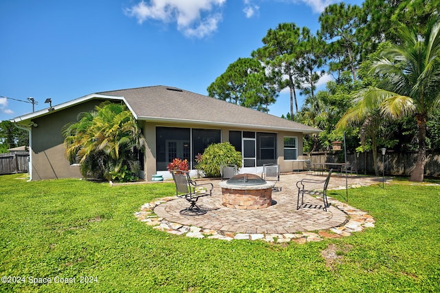 back of property with a sunroom, a patio, an outdoor fire pit, and a yard