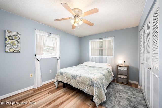 bedroom featuring ceiling fan, hardwood / wood-style flooring, a closet, and a textured ceiling