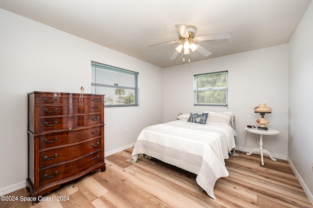 bedroom featuring light wood-type flooring, ceiling fan, and a textured ceiling