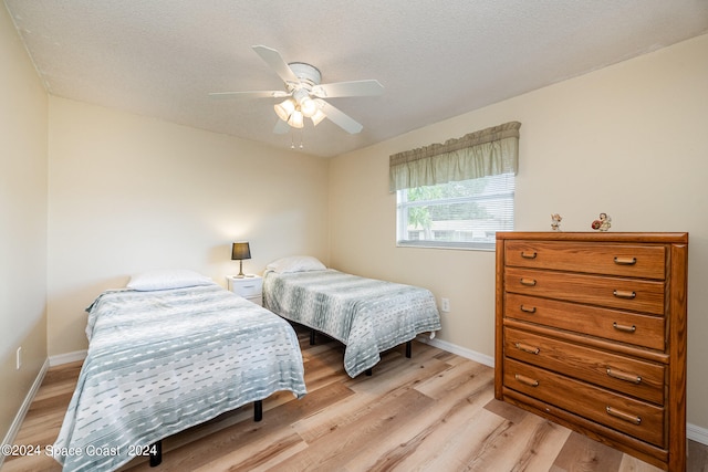 bedroom with light hardwood / wood-style flooring, ceiling fan, and a textured ceiling