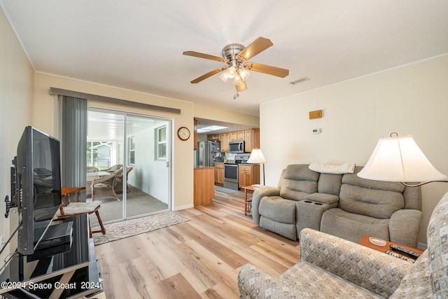 living room featuring ornamental molding, light wood-type flooring, and ceiling fan