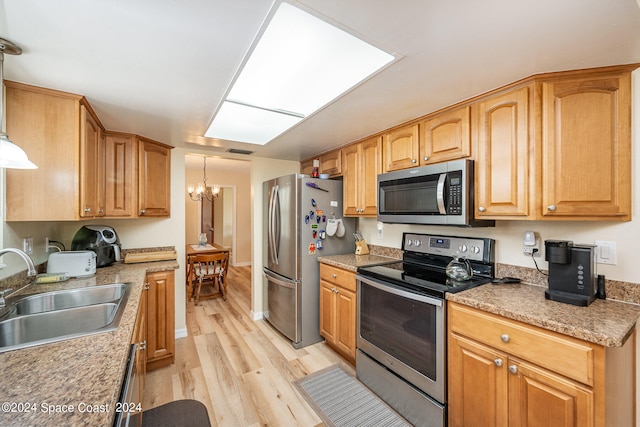 kitchen with light wood-type flooring, a chandelier, sink, hanging light fixtures, and appliances with stainless steel finishes