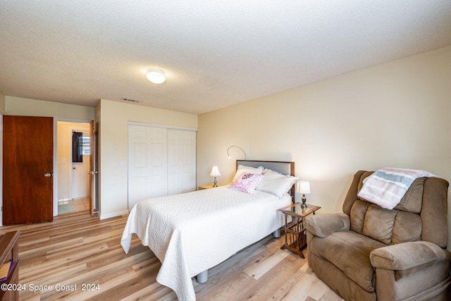 bedroom featuring light wood-type flooring, a closet, and a textured ceiling