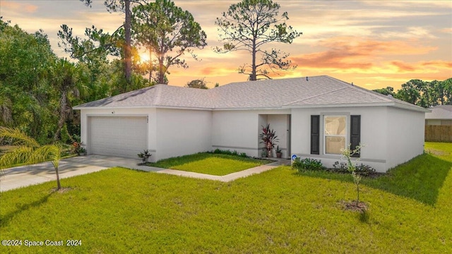 ranch-style house featuring a garage and a yard