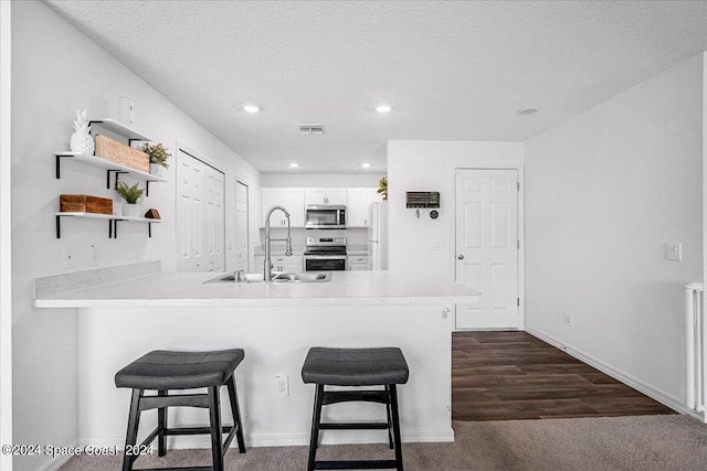 kitchen with white cabinetry, a breakfast bar, kitchen peninsula, stainless steel appliances, and sink