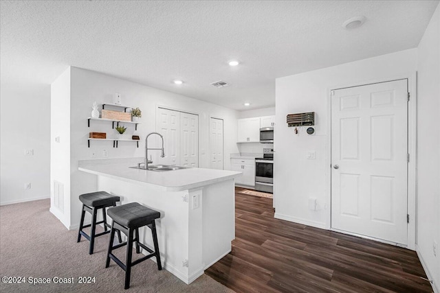 kitchen featuring dark hardwood / wood-style floors, white cabinetry, kitchen peninsula, a kitchen bar, and stainless steel appliances