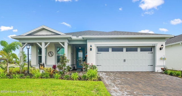 view of front of property featuring a front yard, decorative driveway, roof with shingles, stucco siding, and an attached garage