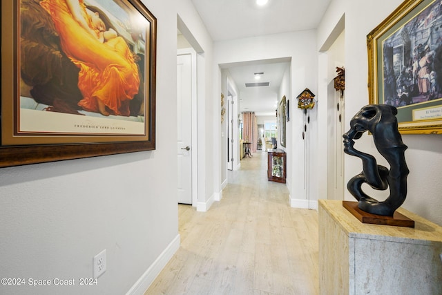 corridor with baseboards and light wood finished floors