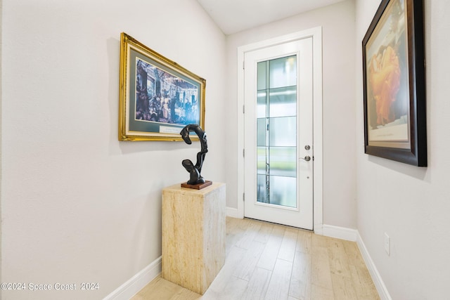 doorway with light wood-type flooring and baseboards