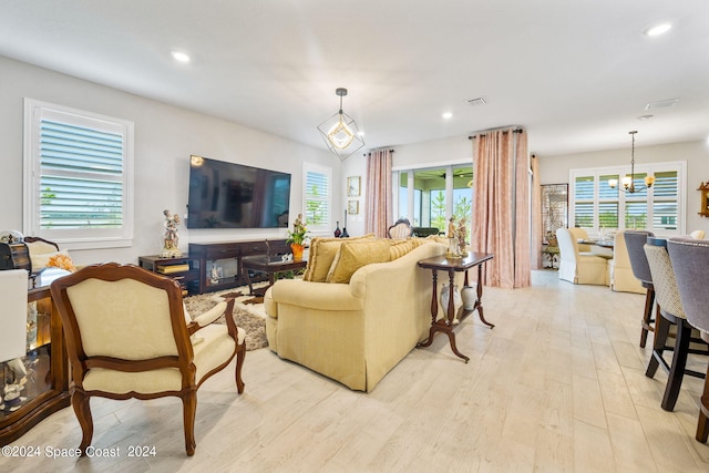 living room with light wood-type flooring, an inviting chandelier, and a wealth of natural light