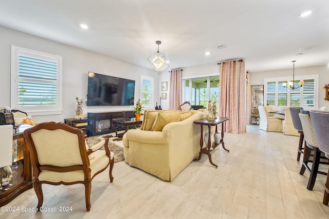 living area with recessed lighting, a wealth of natural light, light wood finished floors, and a notable chandelier