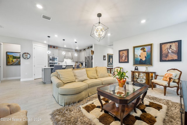 living room with sink, a chandelier, and light hardwood / wood-style floors