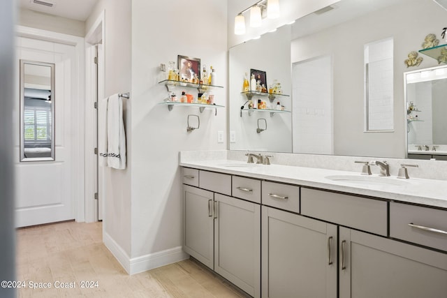 bathroom with double vanity, visible vents, a sink, and wood finished floors