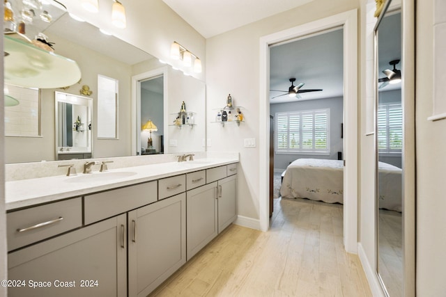 ensuite bathroom featuring a sink, ceiling fan, ensuite bath, and wood finished floors