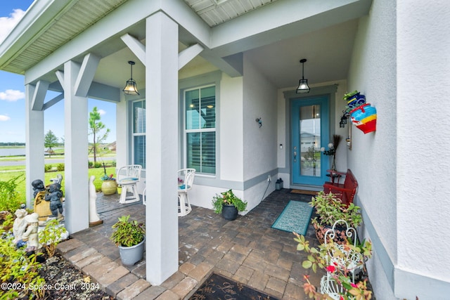 property entrance with covered porch and stucco siding