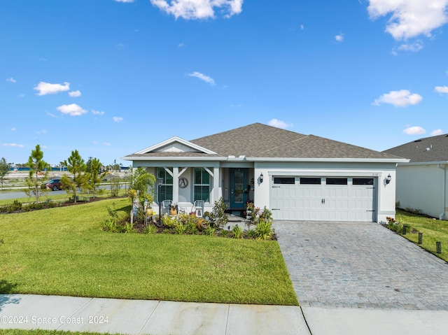 ranch-style home featuring covered porch, an attached garage, decorative driveway, and a front yard