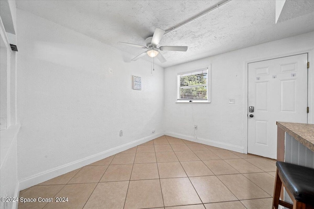 tiled spare room with ceiling fan and a textured ceiling