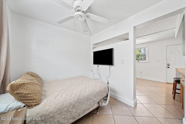 tiled bedroom with ceiling fan and a textured ceiling