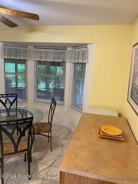 tiled dining space featuring ceiling fan and a textured ceiling