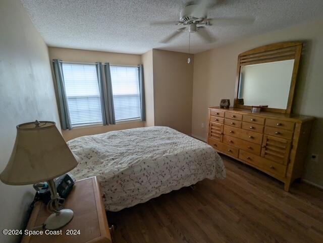 bedroom featuring dark wood-type flooring, a textured ceiling, and ceiling fan