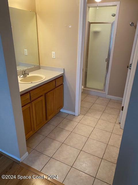 bathroom with tile patterned flooring, walk in shower, and vanity