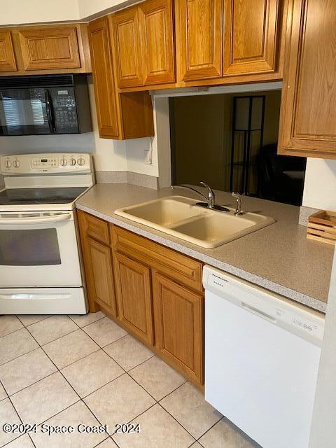 kitchen featuring light tile patterned flooring, white appliances, and sink