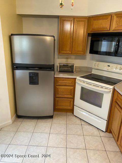 kitchen featuring stainless steel fridge, light tile patterned floors, and electric range