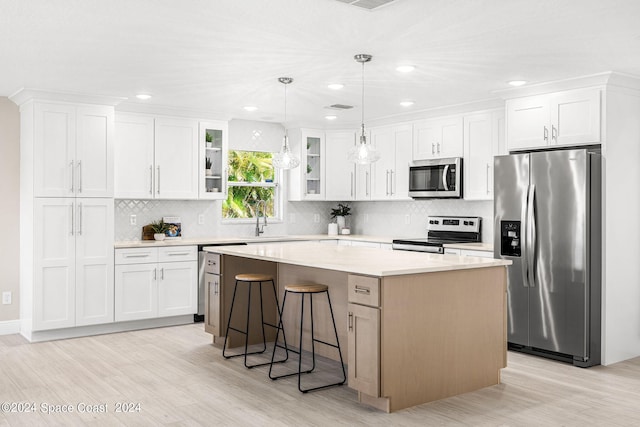 kitchen featuring white cabinetry, appliances with stainless steel finishes, a center island, and hanging light fixtures