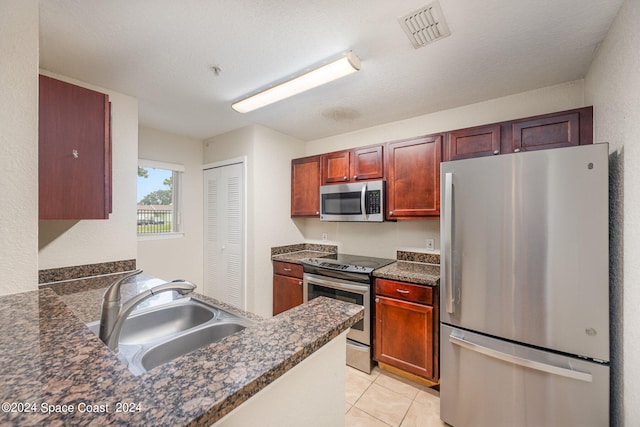 kitchen featuring light tile patterned floors, sink, kitchen peninsula, a textured ceiling, and appliances with stainless steel finishes