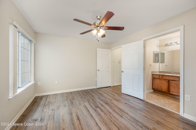 unfurnished bedroom featuring ceiling fan, light wood-type flooring, ensuite bath, and sink