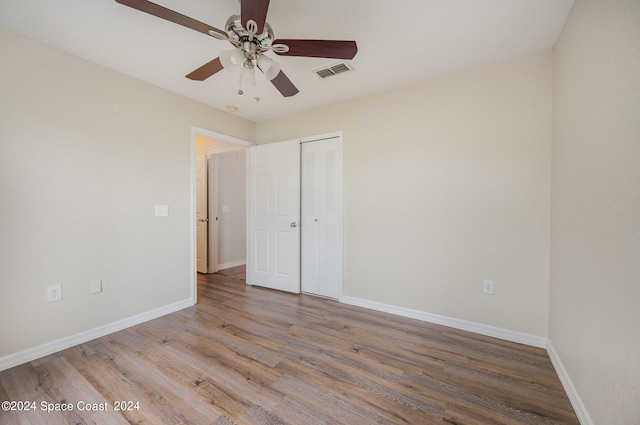 unfurnished bedroom with wood-type flooring, ceiling fan, and a closet