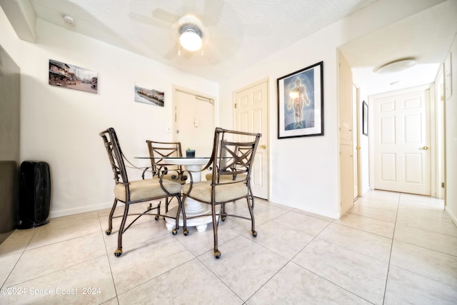 tiled dining room featuring ceiling fan and a textured ceiling