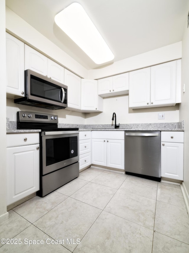 kitchen featuring stainless steel appliances, white cabinetry, and light tile patterned flooring