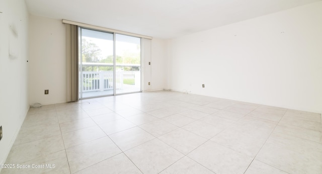 tiled empty room featuring a wall of windows