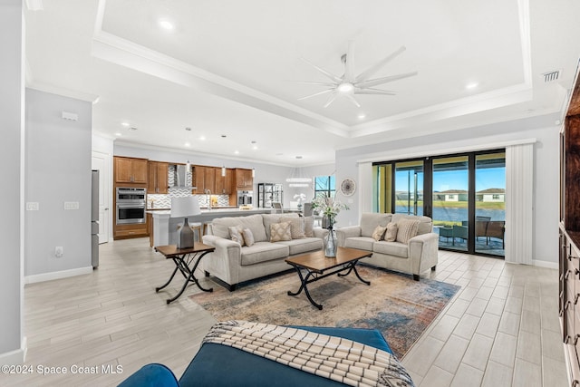 living room featuring a raised ceiling, ceiling fan, light hardwood / wood-style flooring, and crown molding