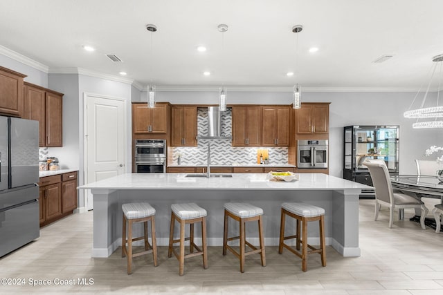 kitchen with appliances with stainless steel finishes, sink, pendant lighting, and an island with sink