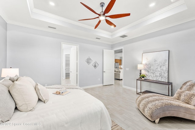 bedroom featuring a walk in closet, ornamental molding, a tray ceiling, ceiling fan, and light hardwood / wood-style flooring