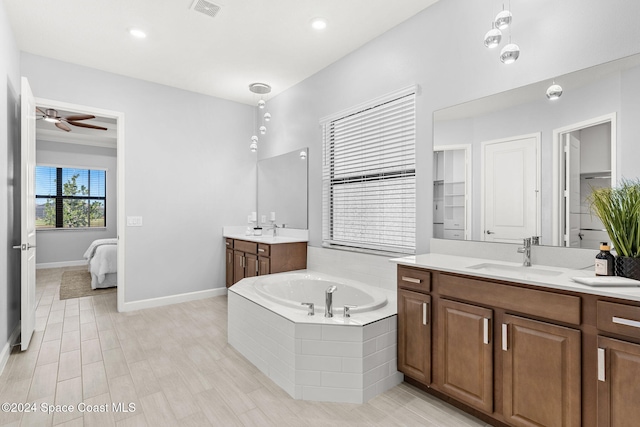 bathroom with hardwood / wood-style floors, vanity, tiled bath, and ceiling fan