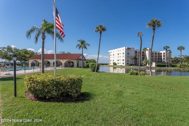 view of community featuring a swimming pool, a yard, and a water view