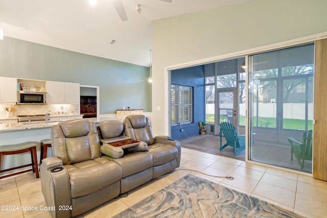 tiled living room featuring ceiling fan and high vaulted ceiling