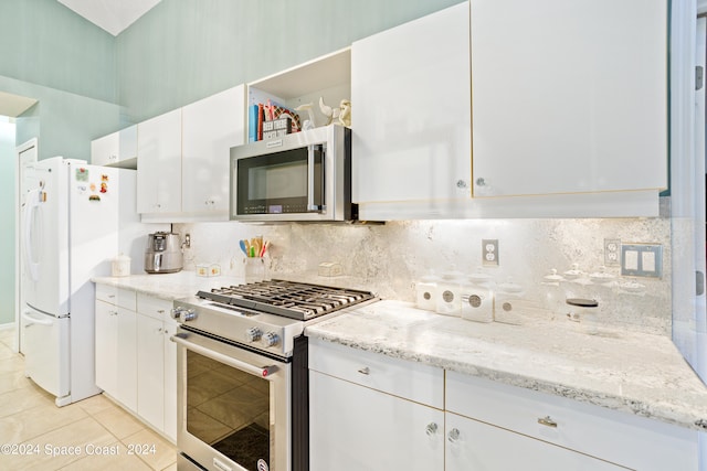 kitchen with light tile patterned flooring, white cabinetry, decorative backsplash, appliances with stainless steel finishes, and light stone countertops