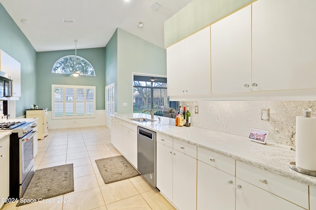 kitchen featuring light stone counters, sink, white cabinetry, appliances with stainless steel finishes, and decorative light fixtures