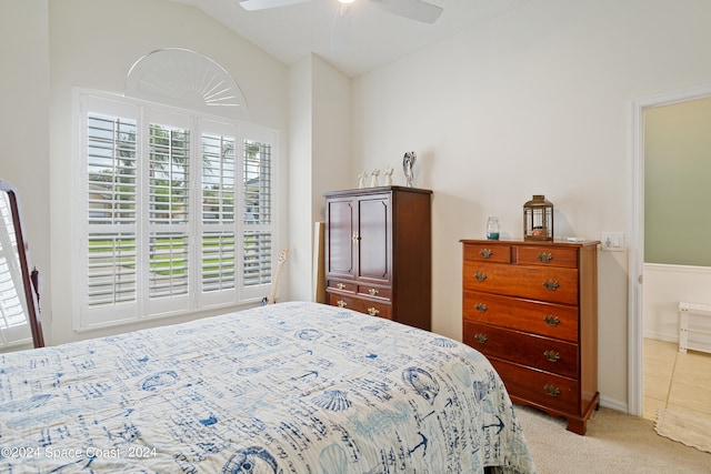 bedroom with ceiling fan, light colored carpet, lofted ceiling, and ensuite bath