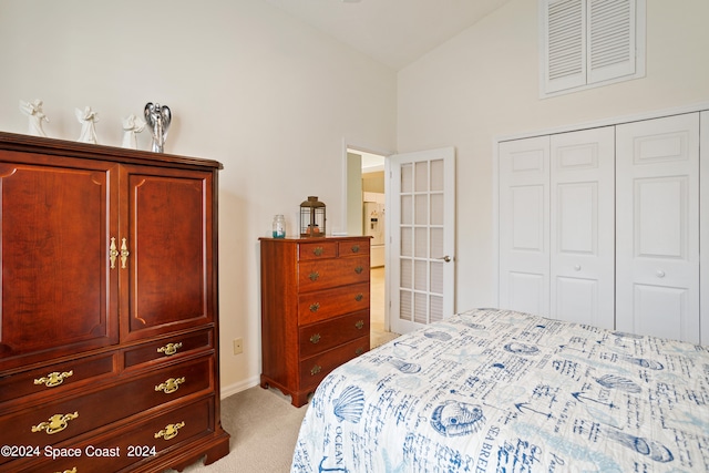 carpeted bedroom with a closet and high vaulted ceiling