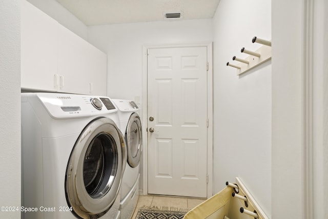 clothes washing area with cabinets, light tile patterned flooring, and washer and dryer