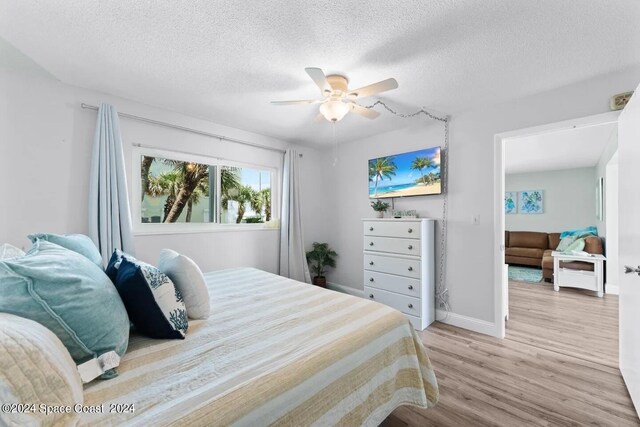 bedroom with light hardwood / wood-style flooring, ceiling fan, and a textured ceiling