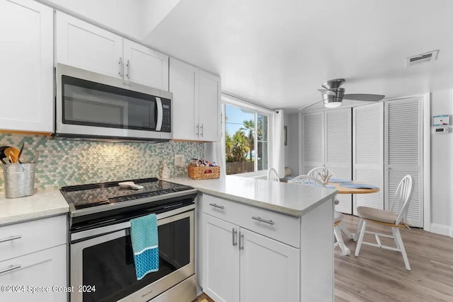 kitchen featuring ceiling fan, kitchen peninsula, tasteful backsplash, white cabinetry, and stainless steel appliances